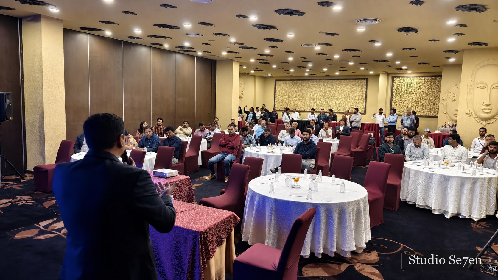 A presenter addressing a large corporate audience in a conference room
