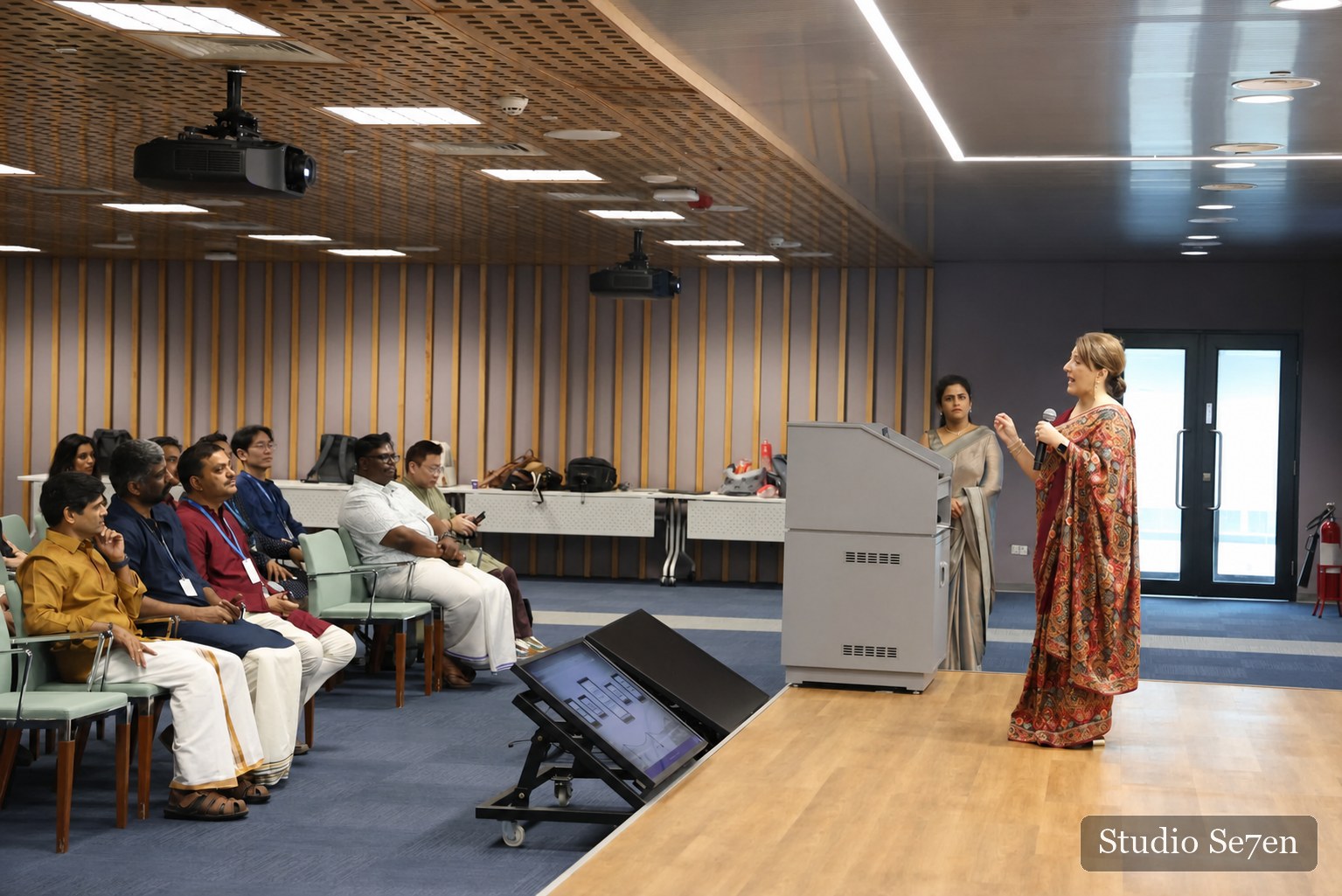 A guest speaker addressing colleagues from the front of a corporate auditorium