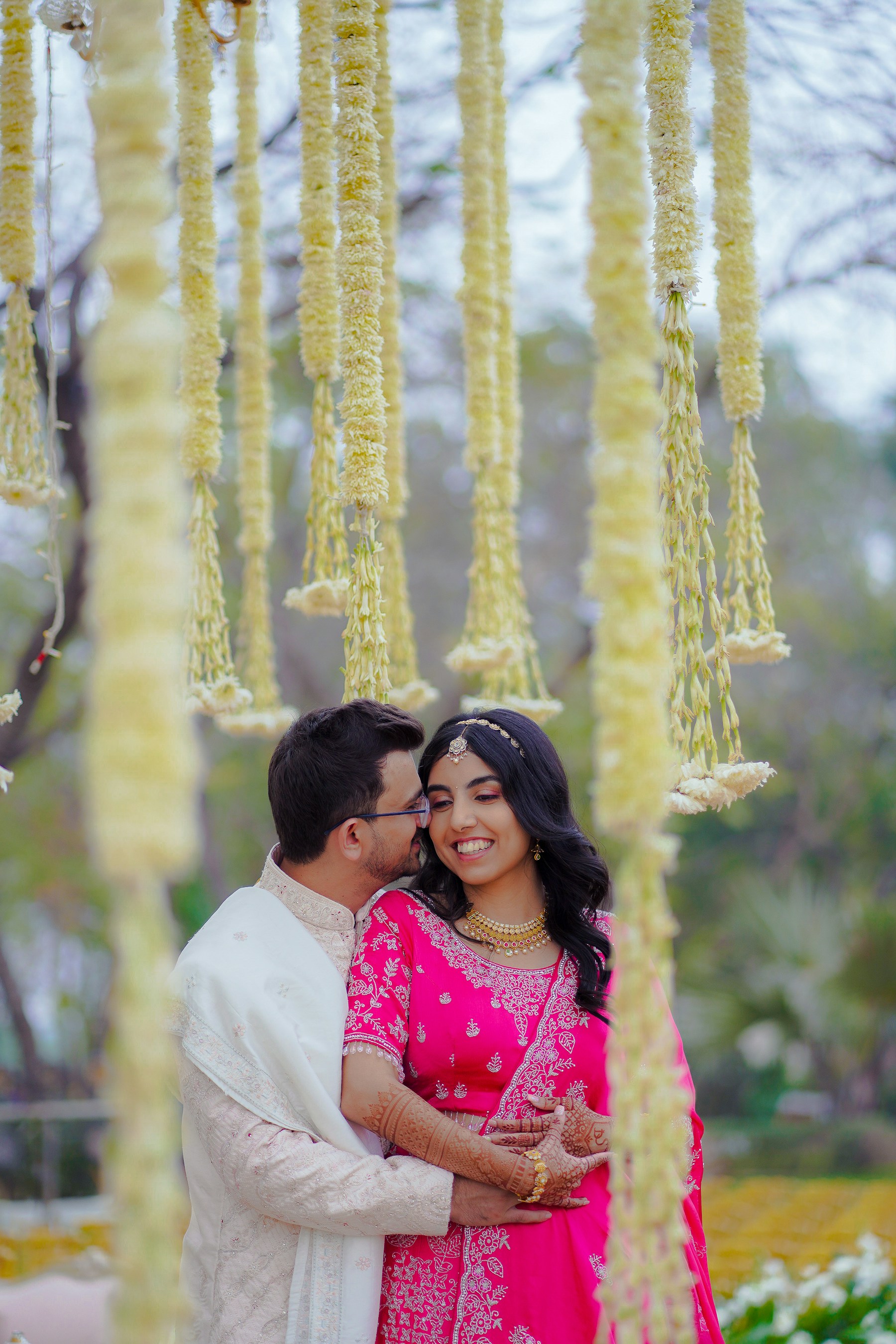 An engaged couple sharing a candid moment beneath flowers