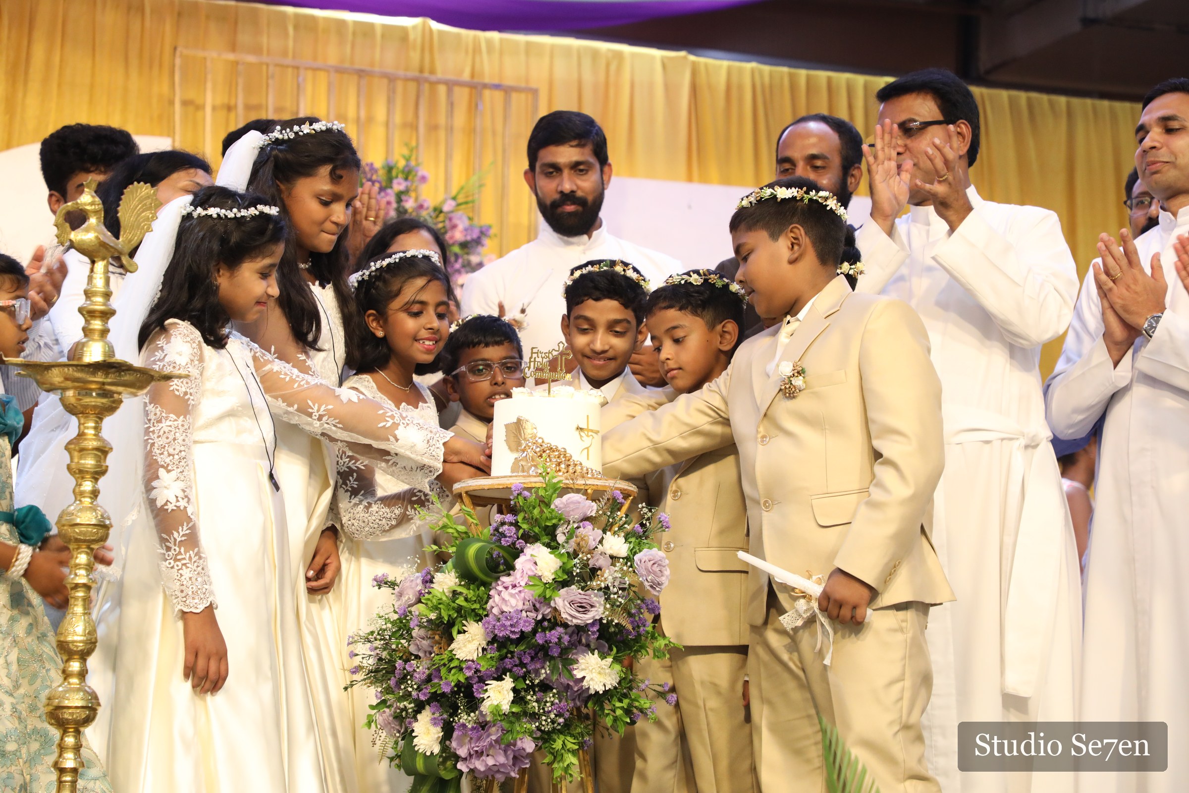Children gathered for a ceremonial cake cutting after their First Holy Communion
