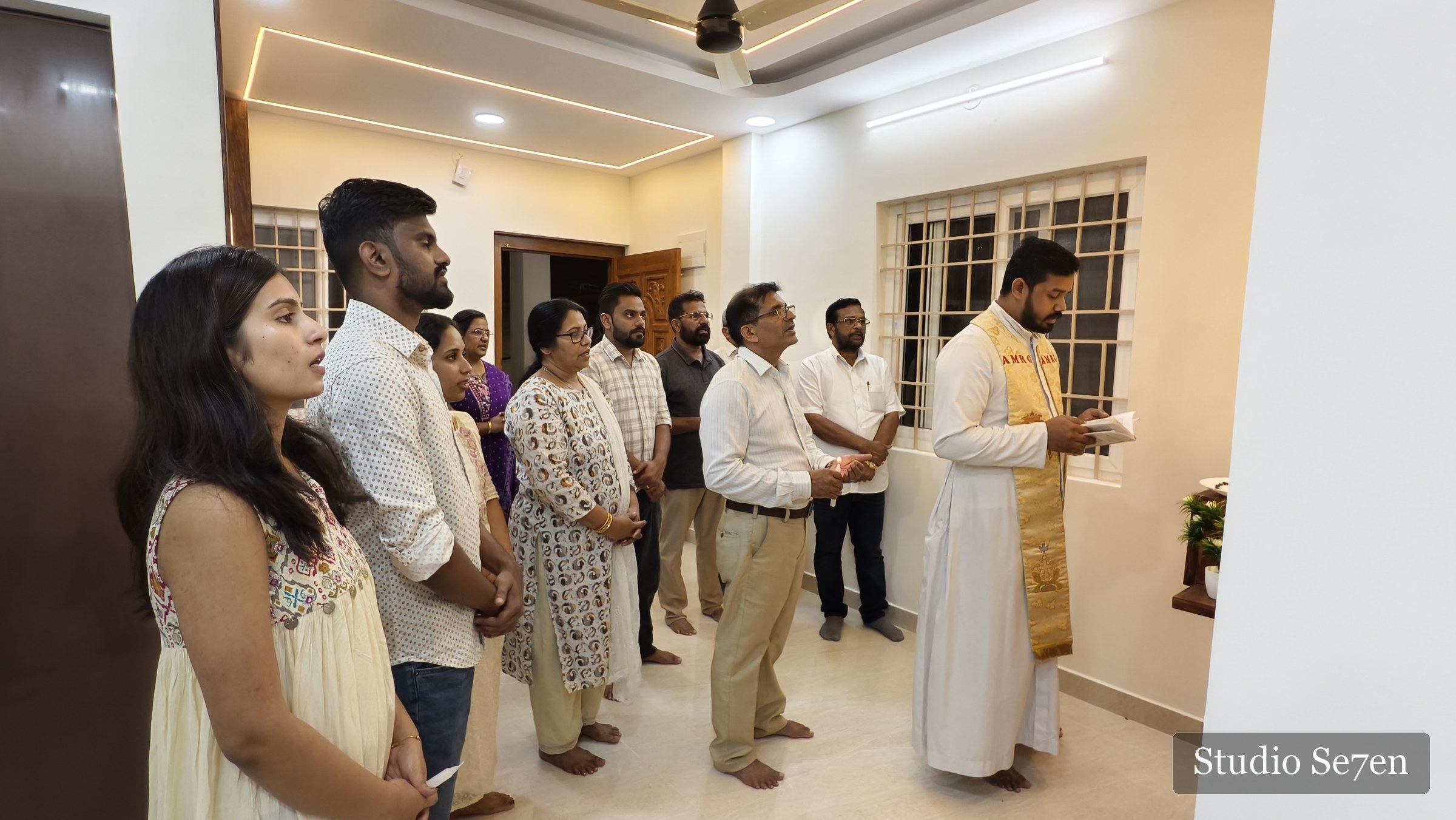Family and friends gathered with a priest for a housewarming prayer