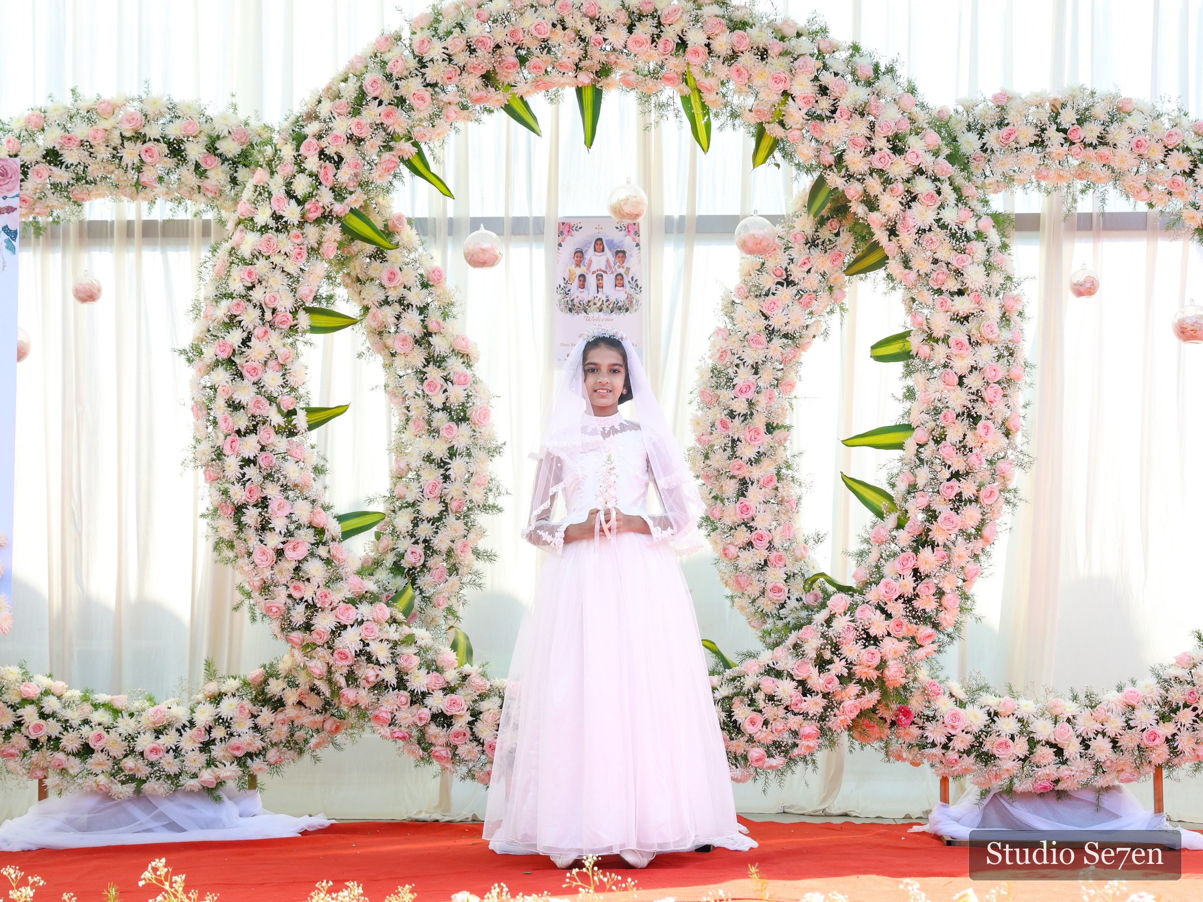 A First Holy Communion portrait framed by pink and white flowers
